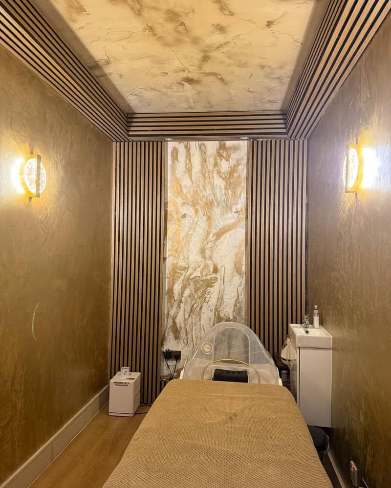 The head spa room at Pure Essentials London, with gold walls and a wood-slat frame